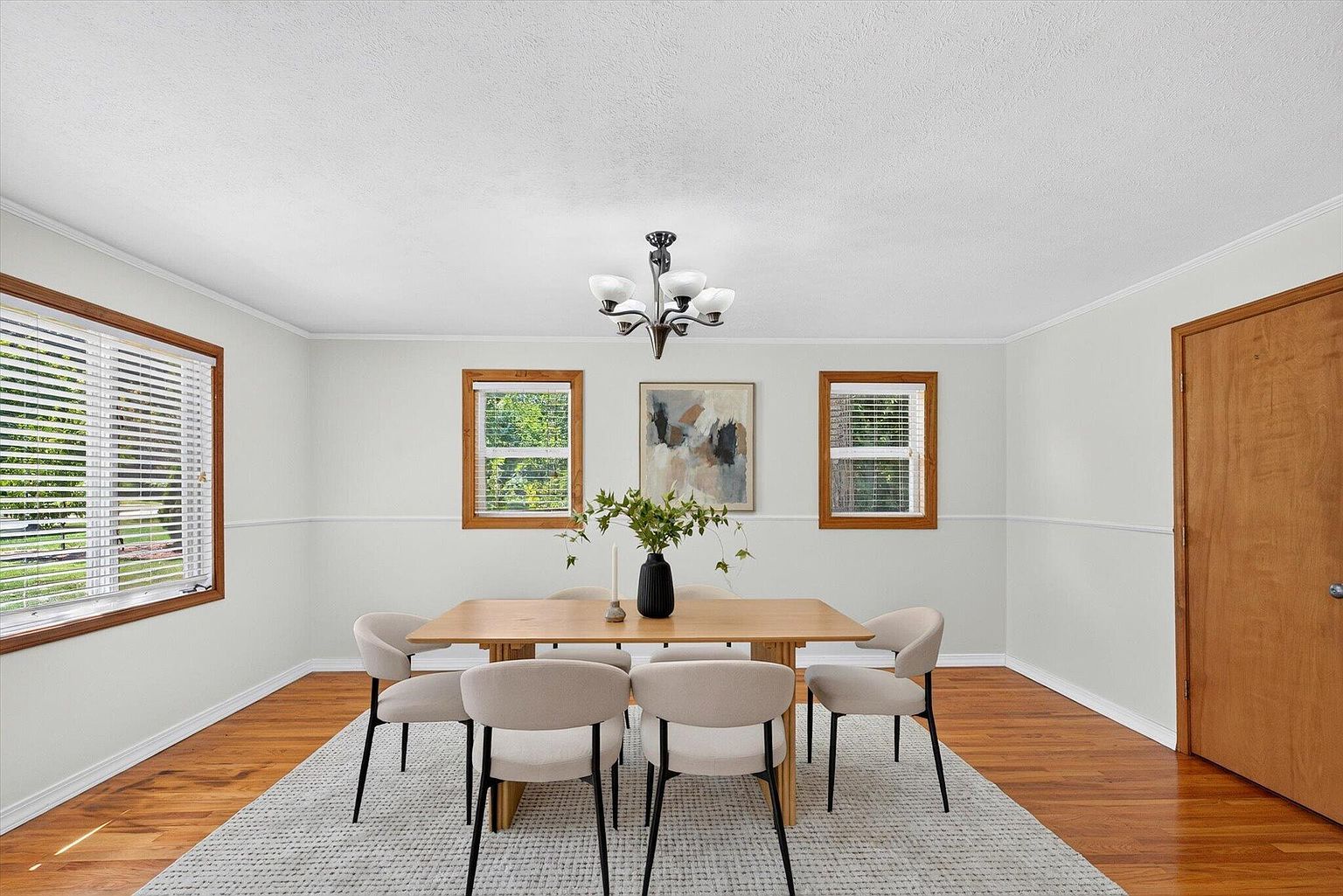 Formal dining room with oak table, cream upholstered chairs and chandelier after home staging at 1345 E Walnut St, Springfield, MO
