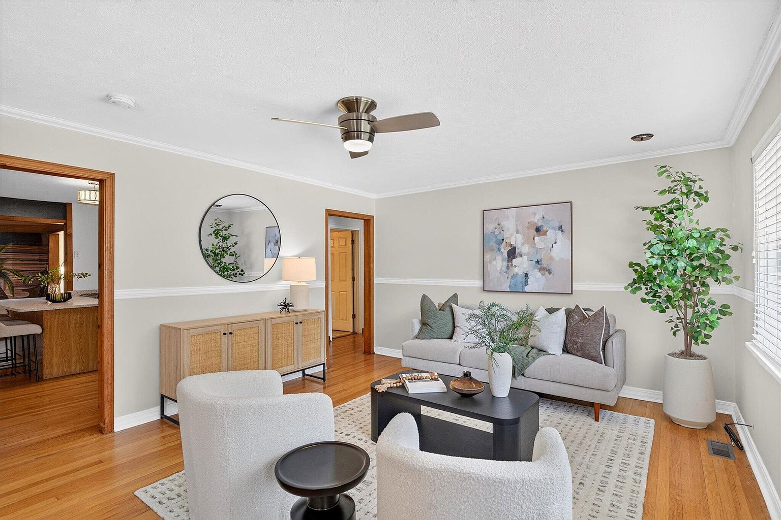 Living room with gray sofa, boucle swivel chairs, black coffee table and rattan sideboard after home staging at 1345 E Walnut St, Springfield, MO