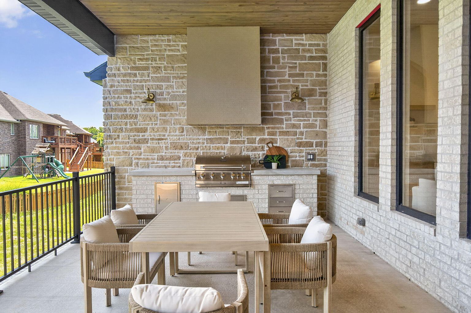 Covered patio with outdoor kitchen, stone wall and staged outdoor dining set after home staging at 2050 N Silver Charm Ave, Springfield, MO