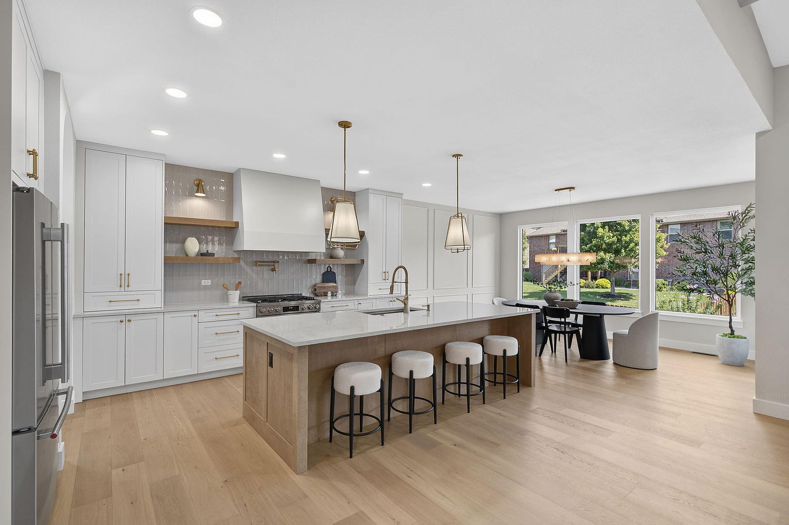 Kitchen with white oak island, white bar stools, brass pendants and dining area by the windows - 2050 N Silver Charm Ave, Springfield, MO