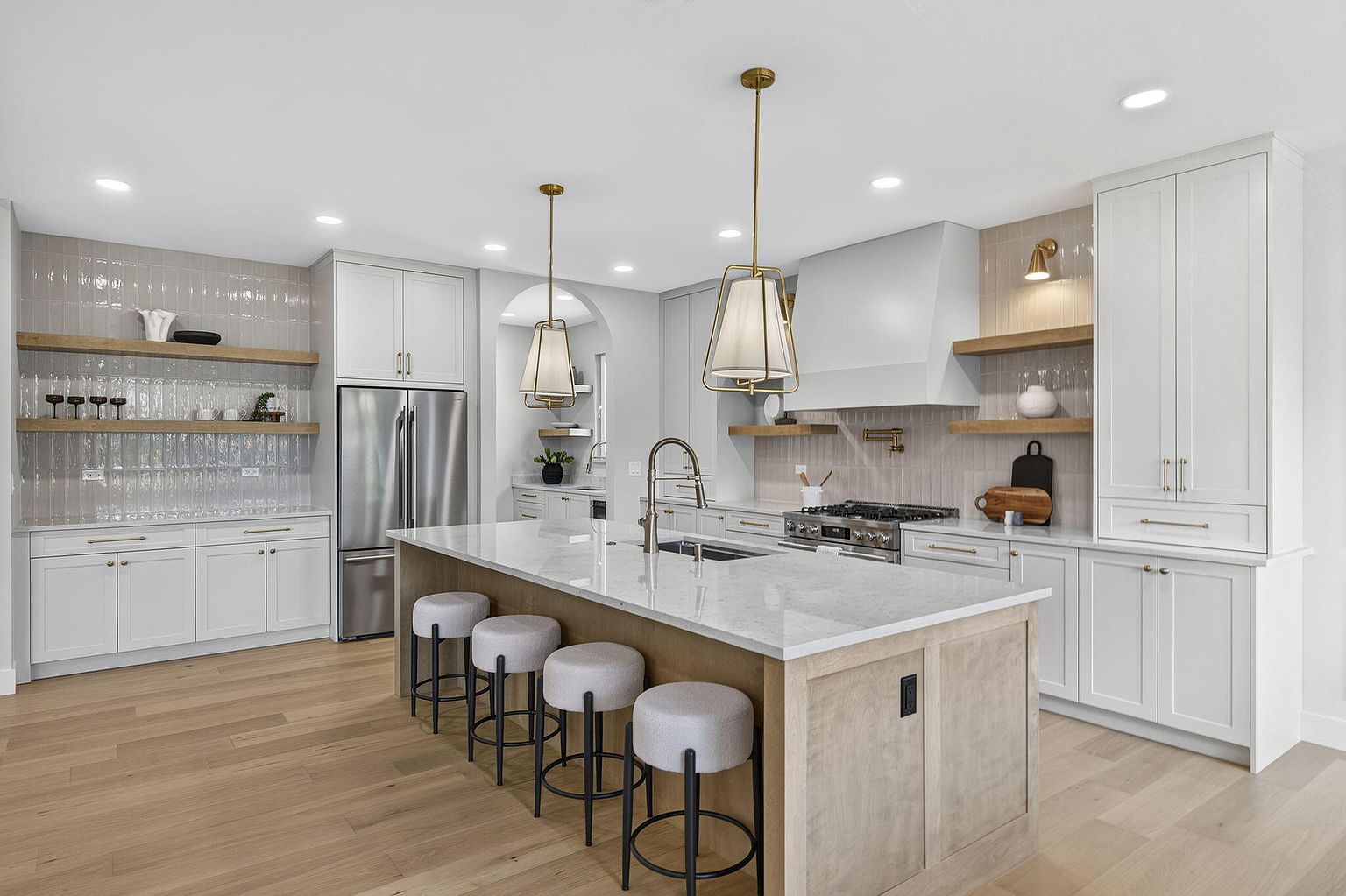 Kitchen with white cabinetry, floating shelves, white oak island and upholstered bar stools after staging at 2050 N Silver Charm Ave, Springfield, MO