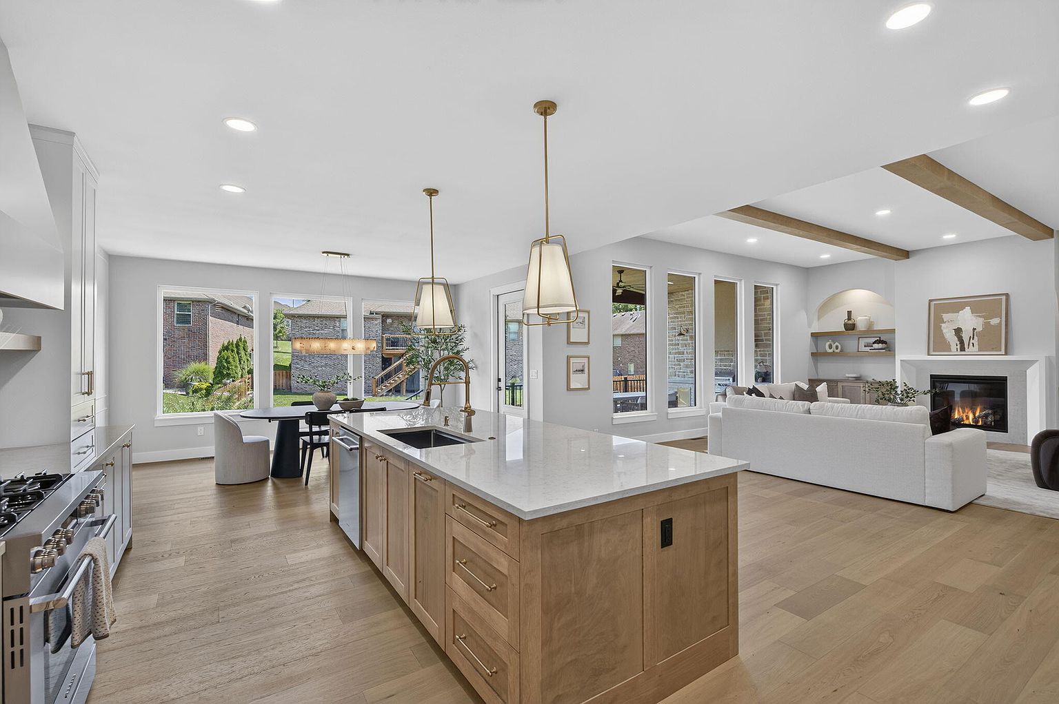 Kitchen island with brass pendants looking across to the staged living room and fireplace - 2050 N Silver Charm Ave, Springfield, MO