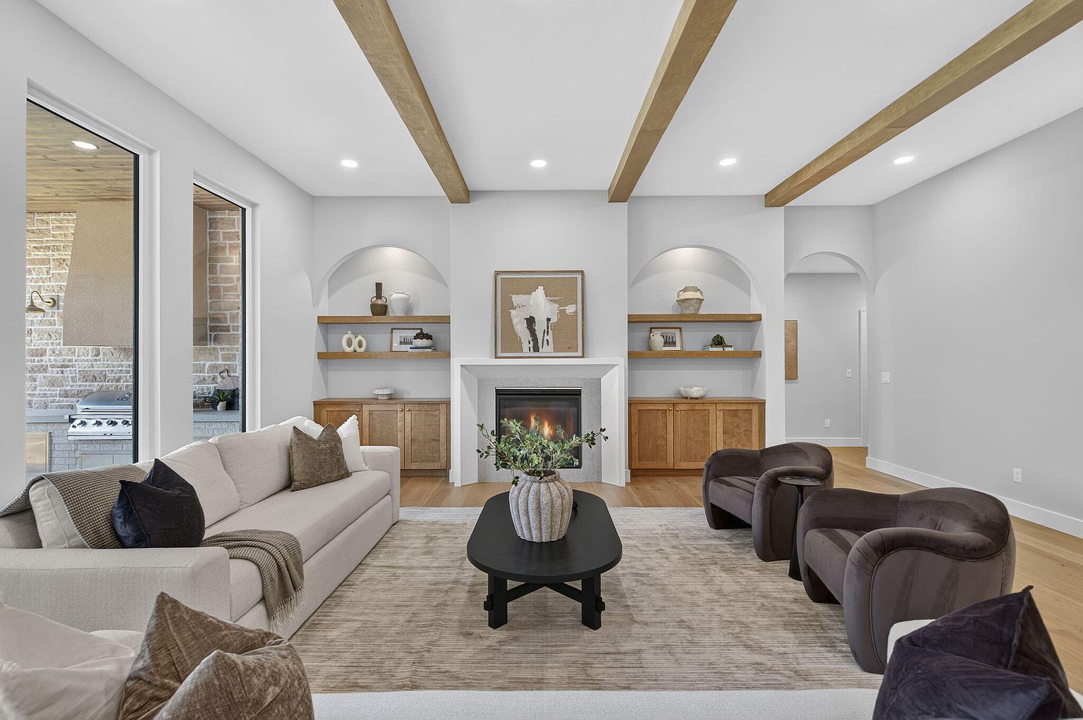 Living room with exposed wood beams, arched built-ins, cream sofa and velvet swivel chairs after home staging at 2050 N Silver Charm Ave, Springfield, MO