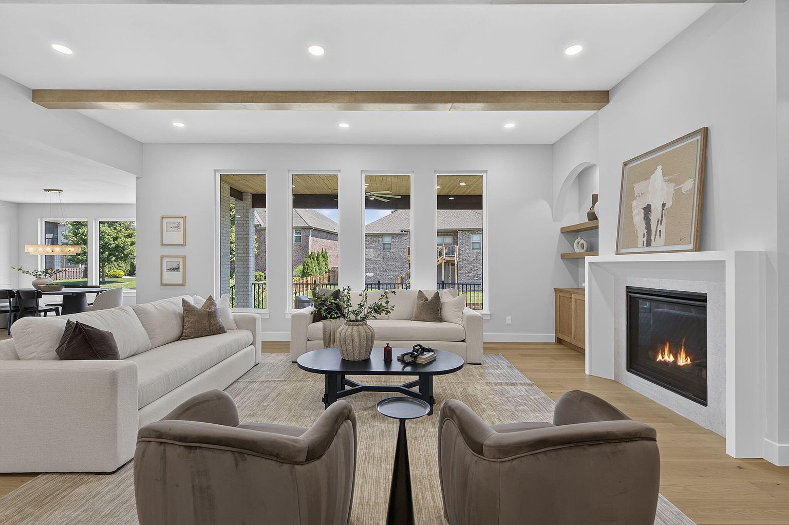 Living room with a wall of windows, white fireplace surround, cream sofas and brown velvet chairs - 2050 N Silver Charm Ave, Springfield, MO home staging