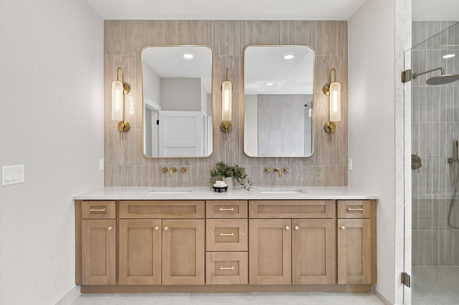 Primary bathroom with white oak double vanity, arched mirrors and brass sconces after home staging at 2050 N Silver Charm Ave, Springfield, MO