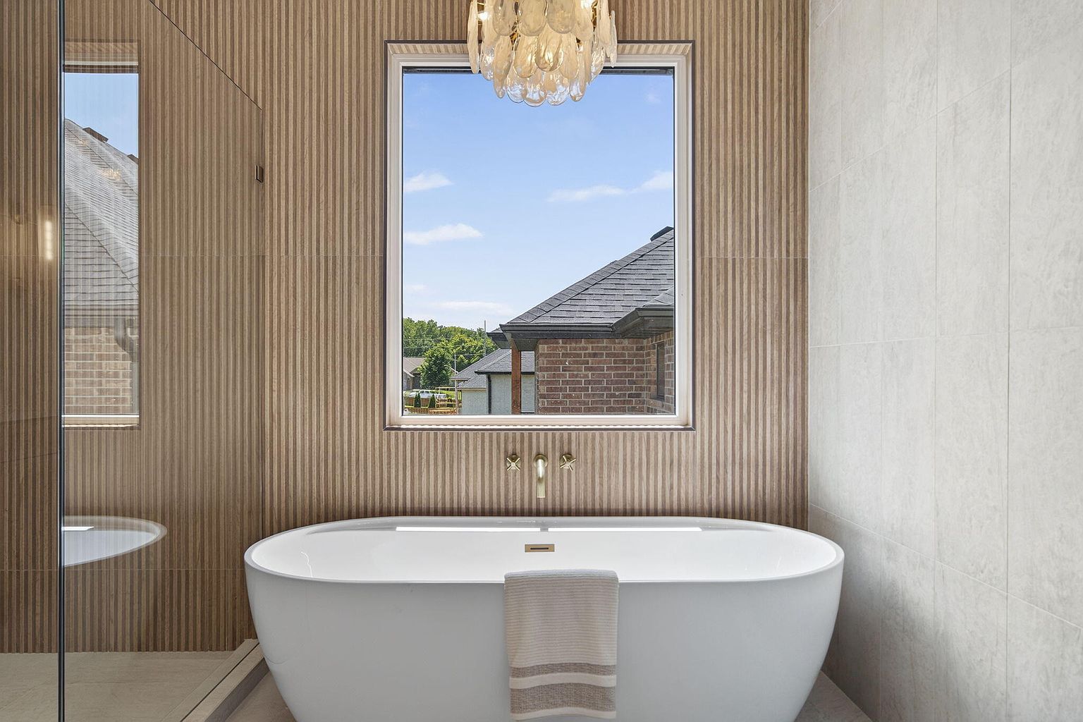 Primary bathroom freestanding tub under a window framed by fluted wood paneling - 2050 N Silver Charm Ave, Springfield, MO home staging