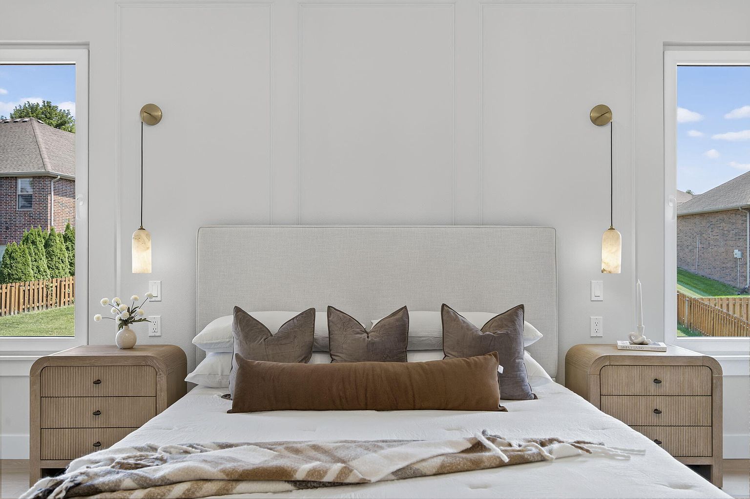Primary bedroom with upholstered headboard, wall sconces, wood nightstands and layered neutral bedding - 2050 N Silver Charm Ave, Springfield, MO