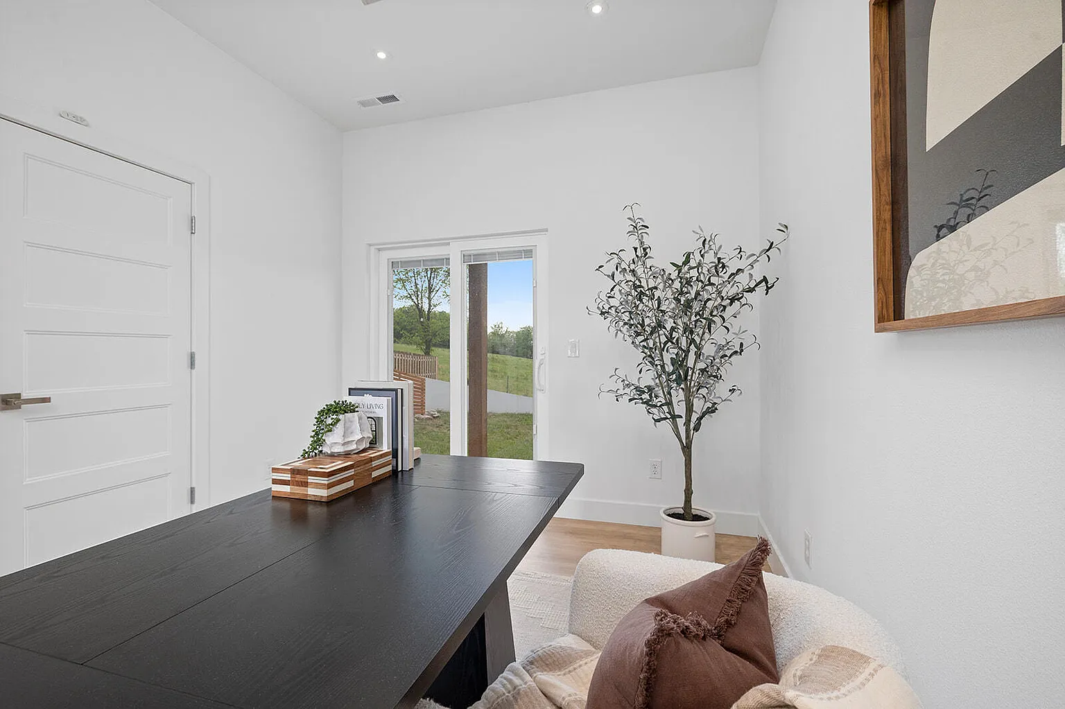 Home office with black desk, olive tree and patio view - 2807 S 14th Ave, Ozark, MO