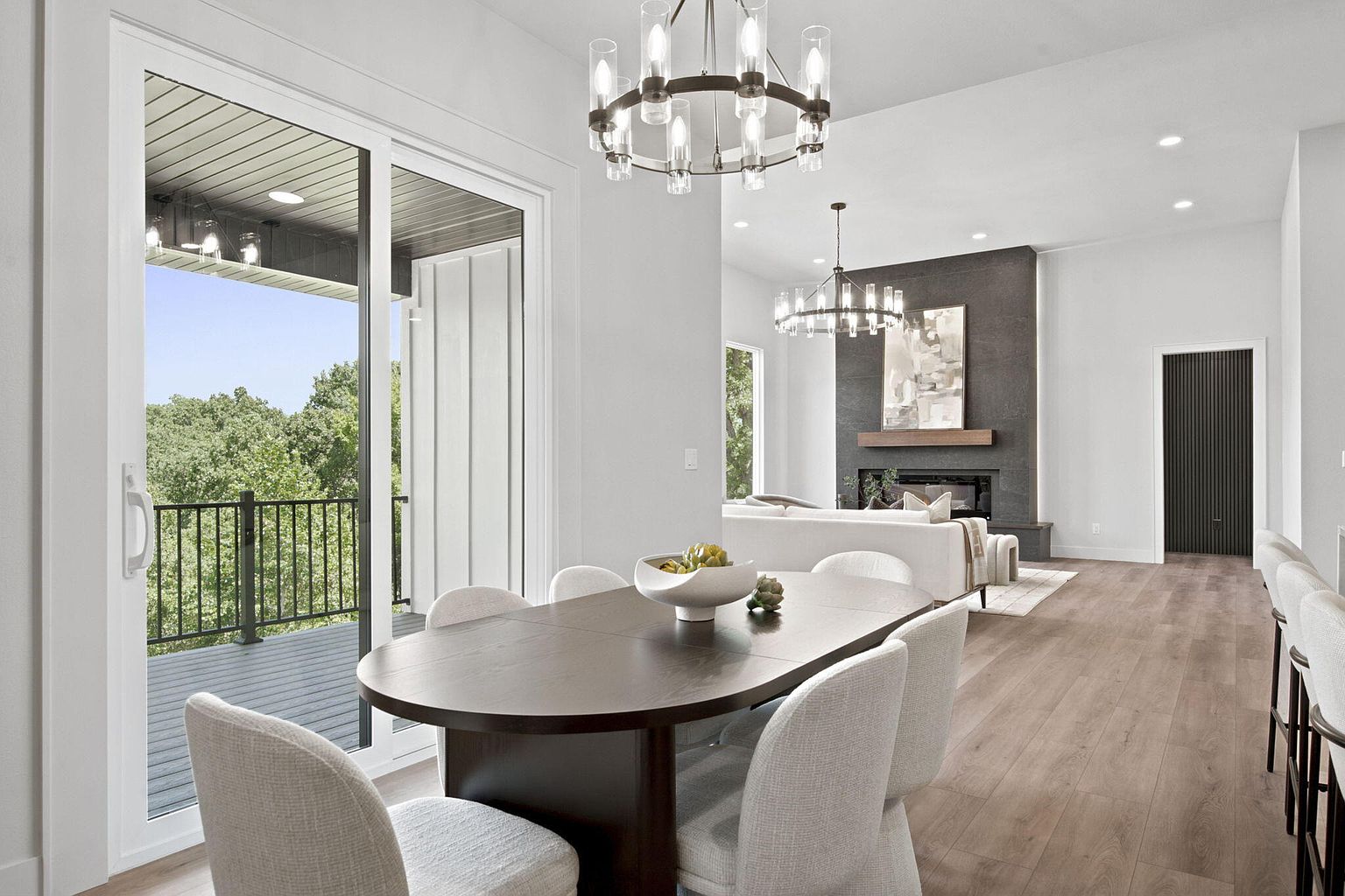 Dining area with oval table, boucle chairs and sliding doors to the deck overlooking the trees - 346 Sunset Dr, Saddlebrooke, MO