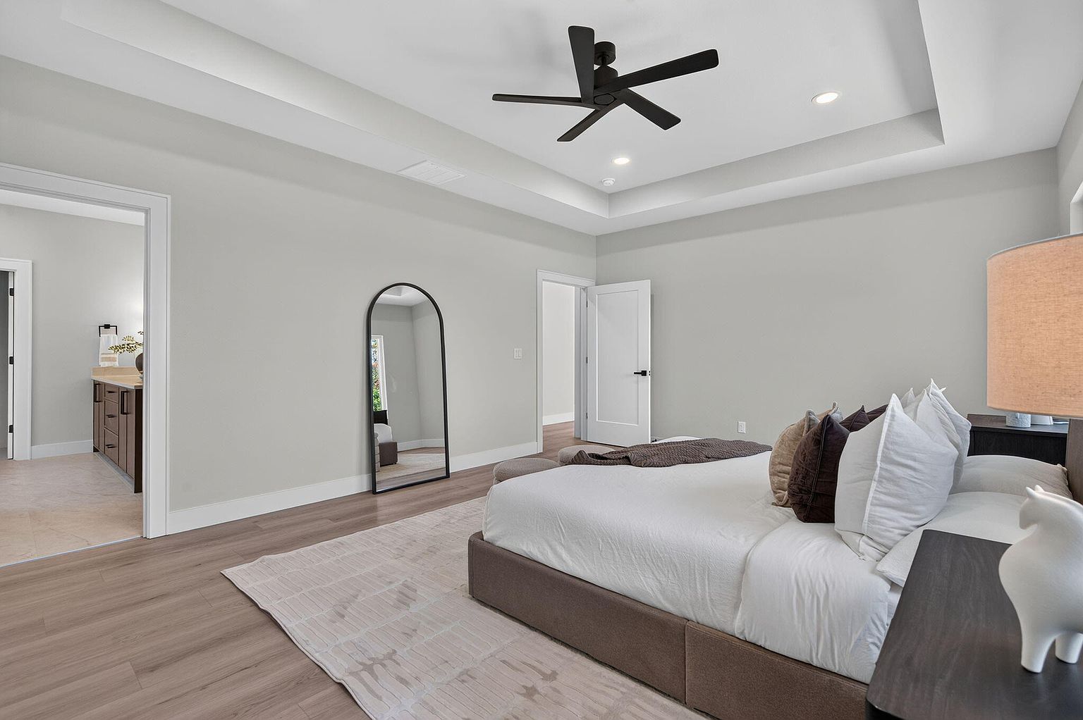 Primary bedroom with arched floor mirror and view into the ensuite bath - 346 Sunset Dr, Saddlebrooke, MO home staging