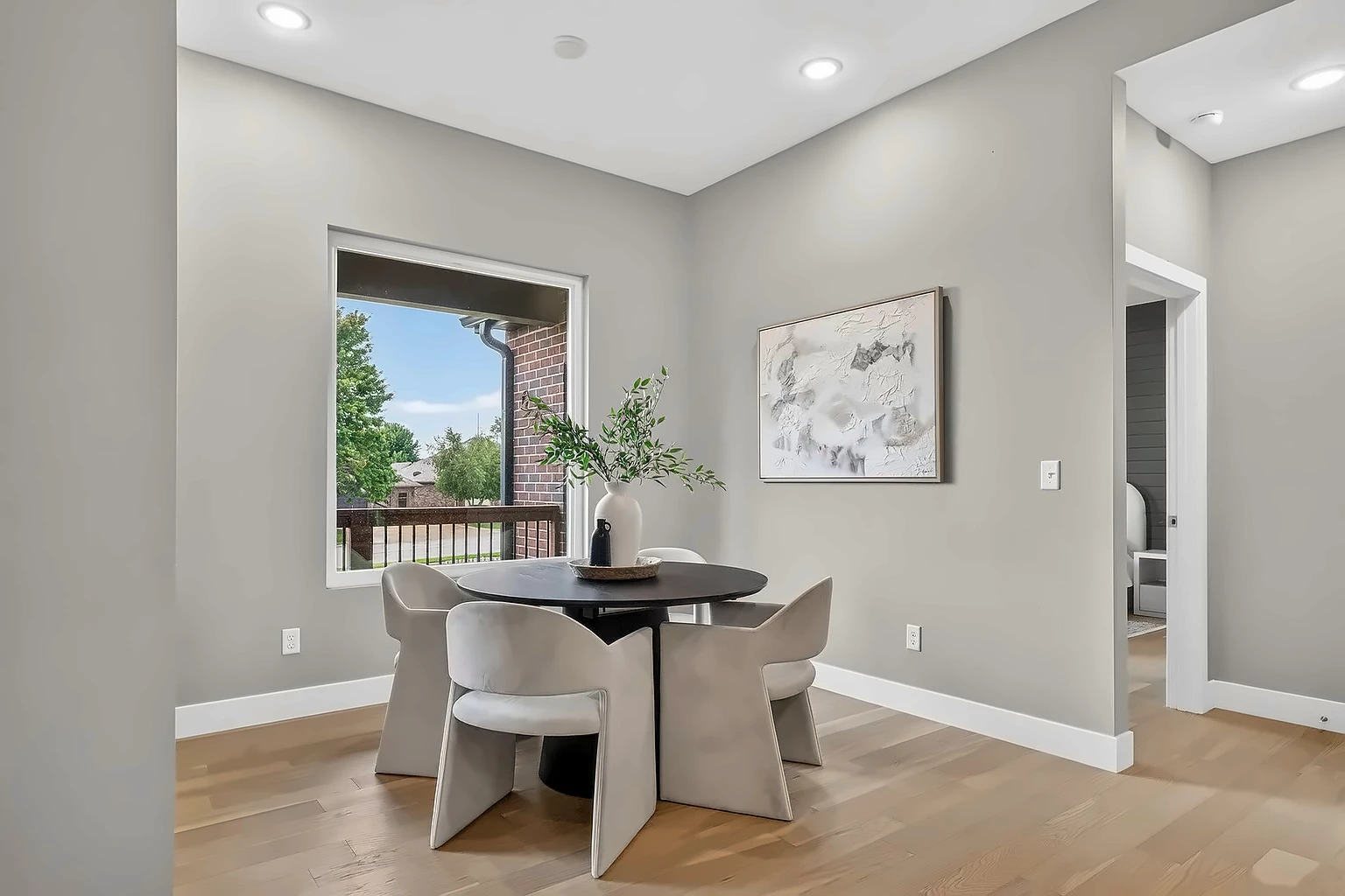 Breakfast nook with round black table, taupe velvet chairs and abstract wall art - 5048 Swale home staging, Springfield, MO