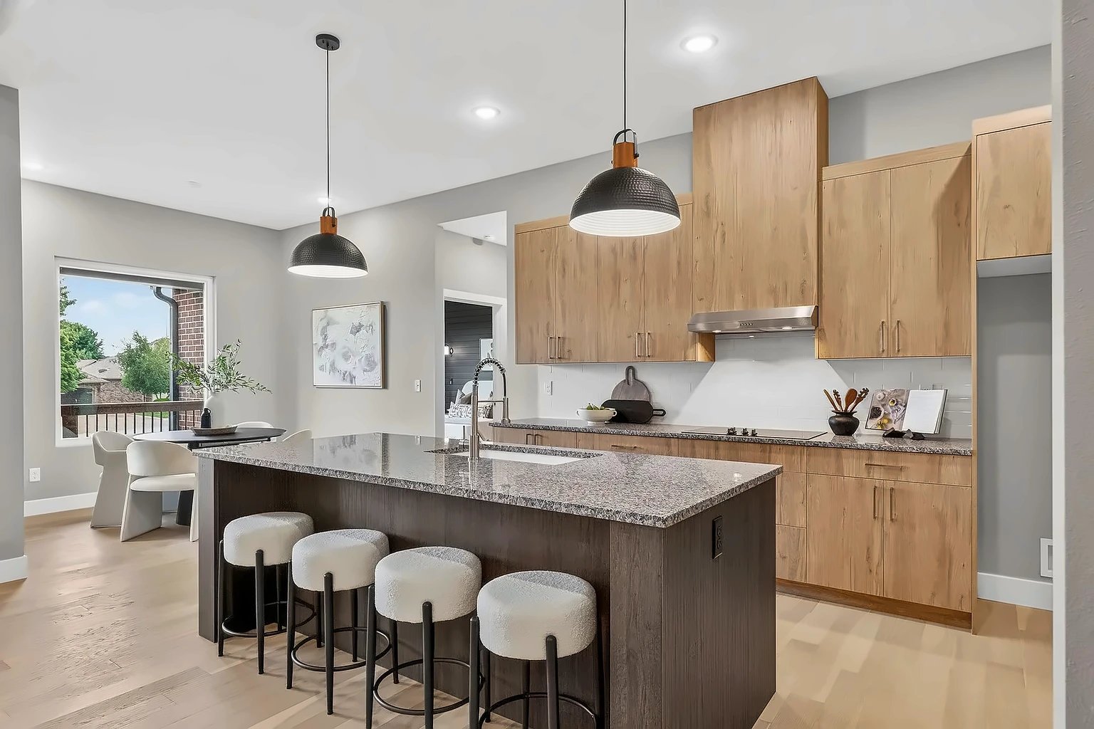 Kitchen with granite island, boucle bar stools, warm wood cabinets and pendant lights after home staging at 5048 Swale, Springfield, MO