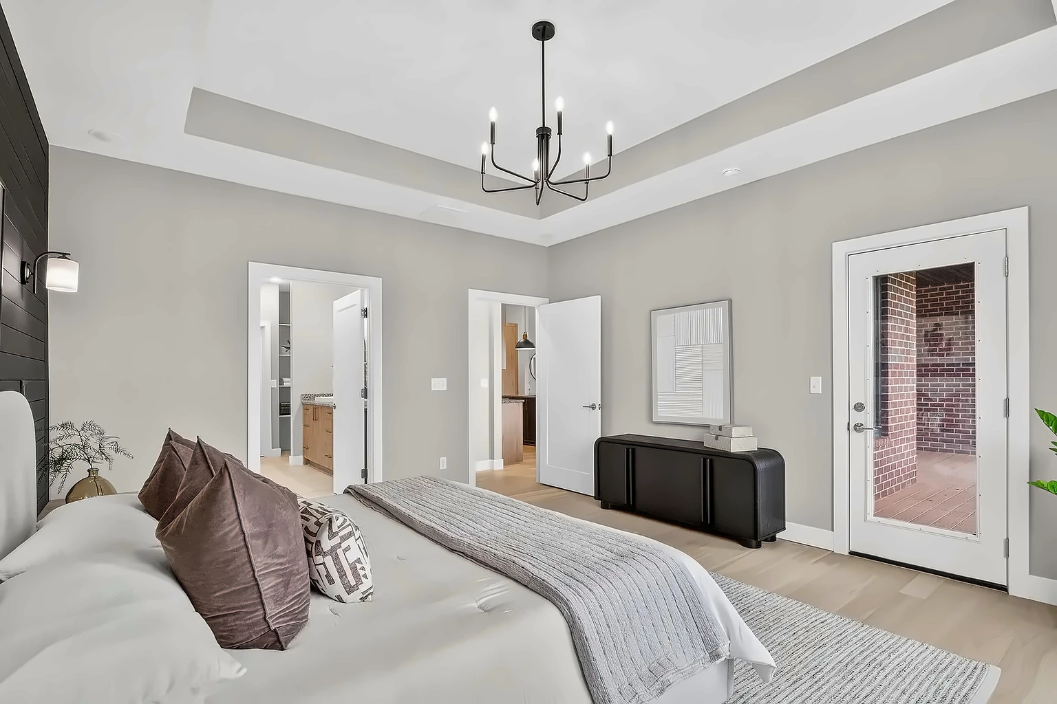 Primary bedroom with black sideboard, ensuite and closet doorways and private brick patio access - 5048 Swale home staging, Springfield, MO