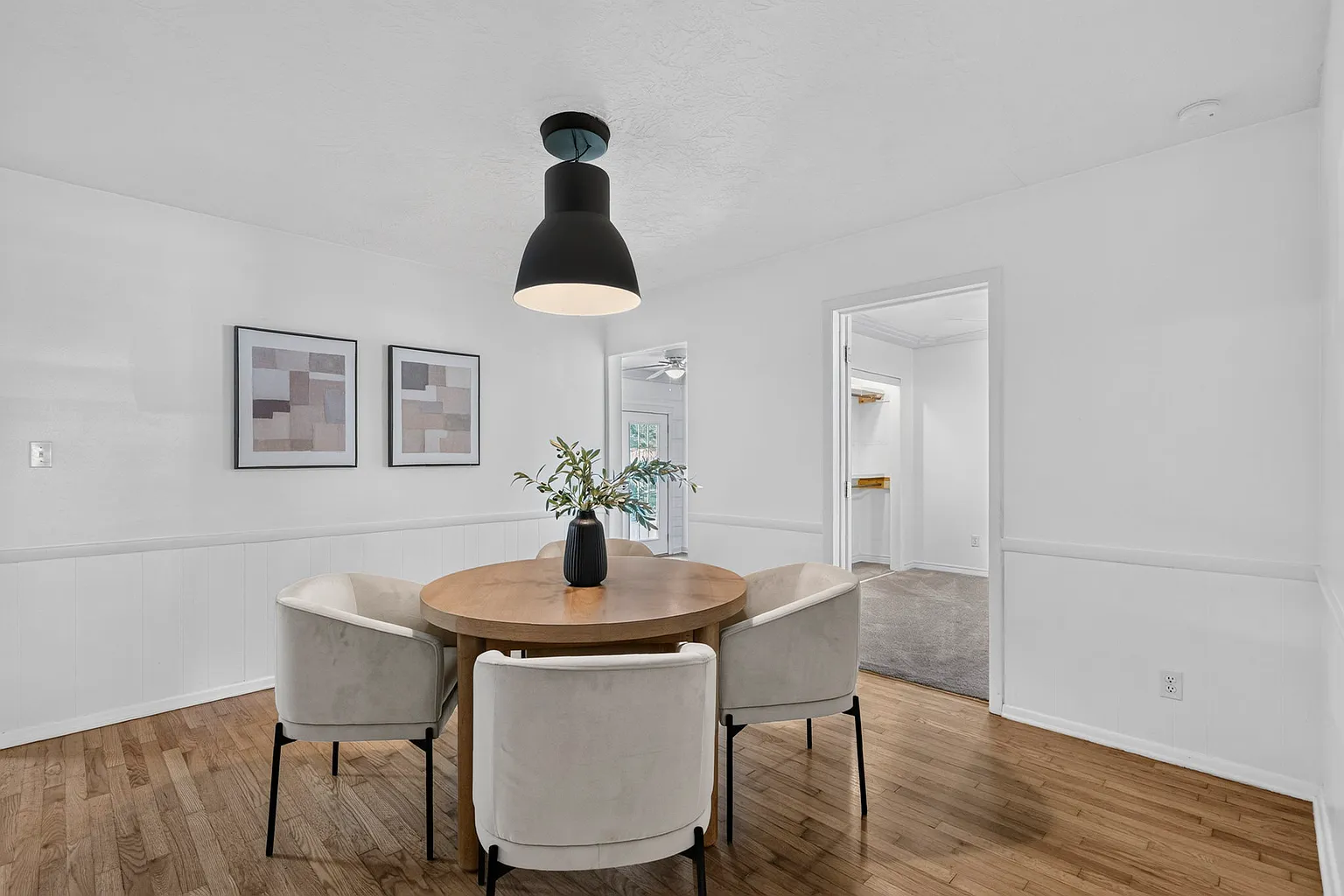 Dining room with round wood table, upholstered chairs and black pendant light - Florence Ave home staging, Springfield, MO