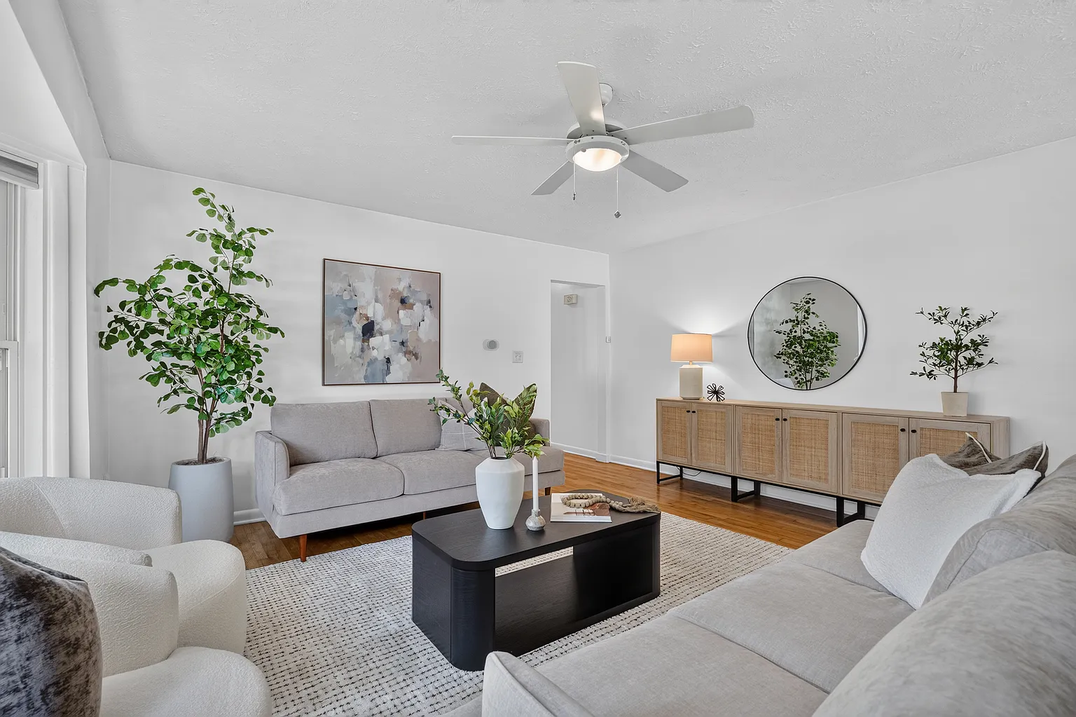 Living room with rattan sideboard, round mirror and greenery styling after staging - Florence Ave, Springfield, MO