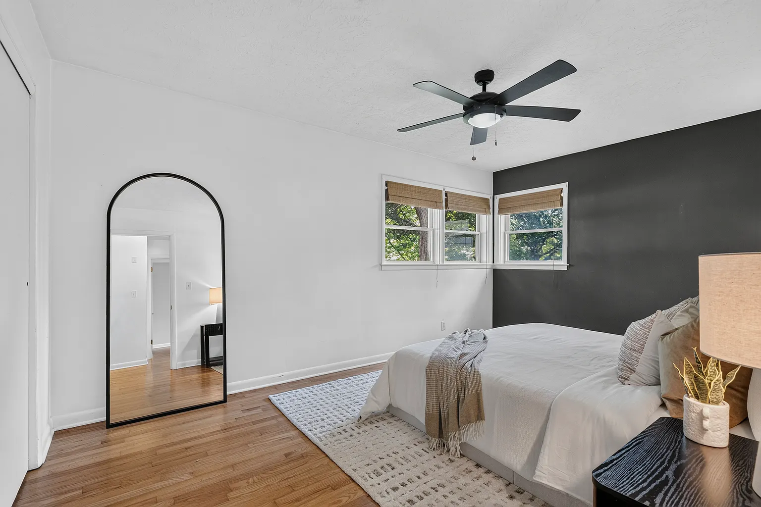 Bedroom with charcoal accent wall, arched floor mirror and ceiling fan after vacant home staging - Florence Ave, Springfield, MO