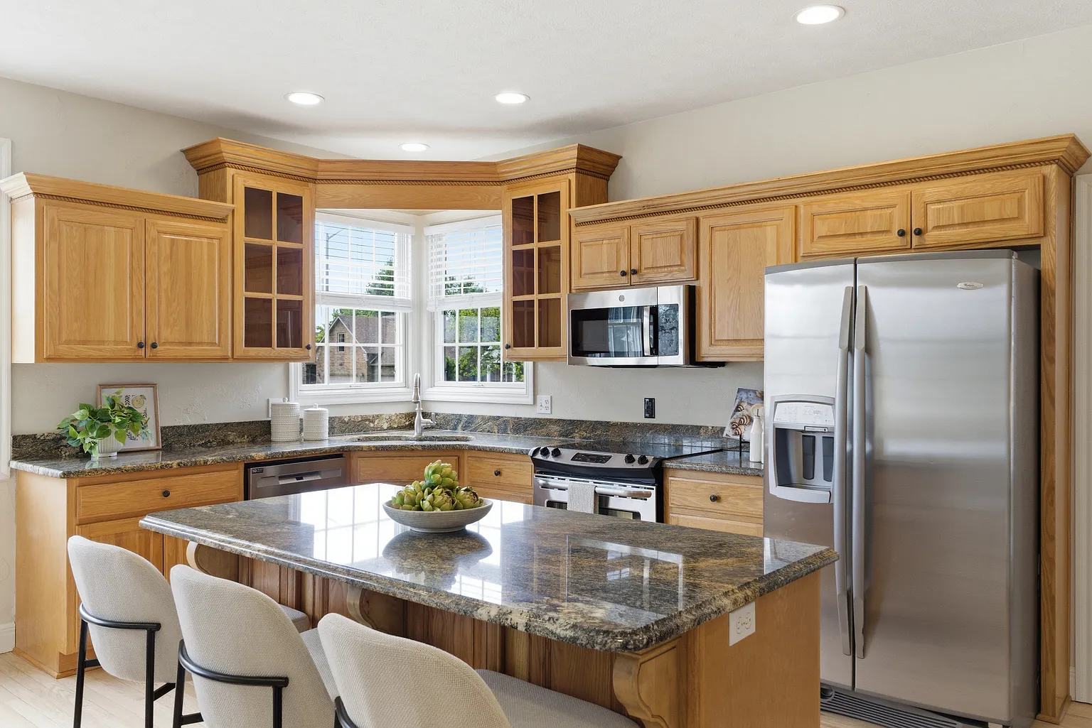 Kitchen granite island with bar stools, oak cabinetry and stainless appliances after home staging - Gaslight Drive, Springfield, MO