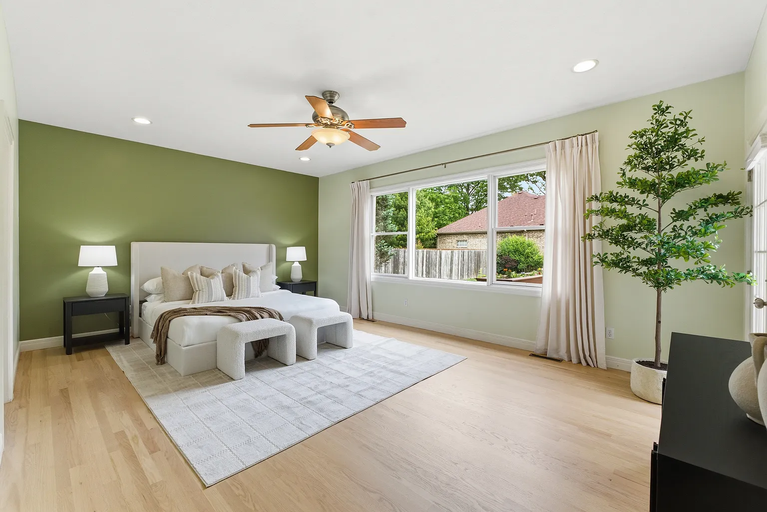 Primary bedroom wide angle with sage green walls, upholstered bed and olive tree after staging - Gaslight Drive, Springfield, MO