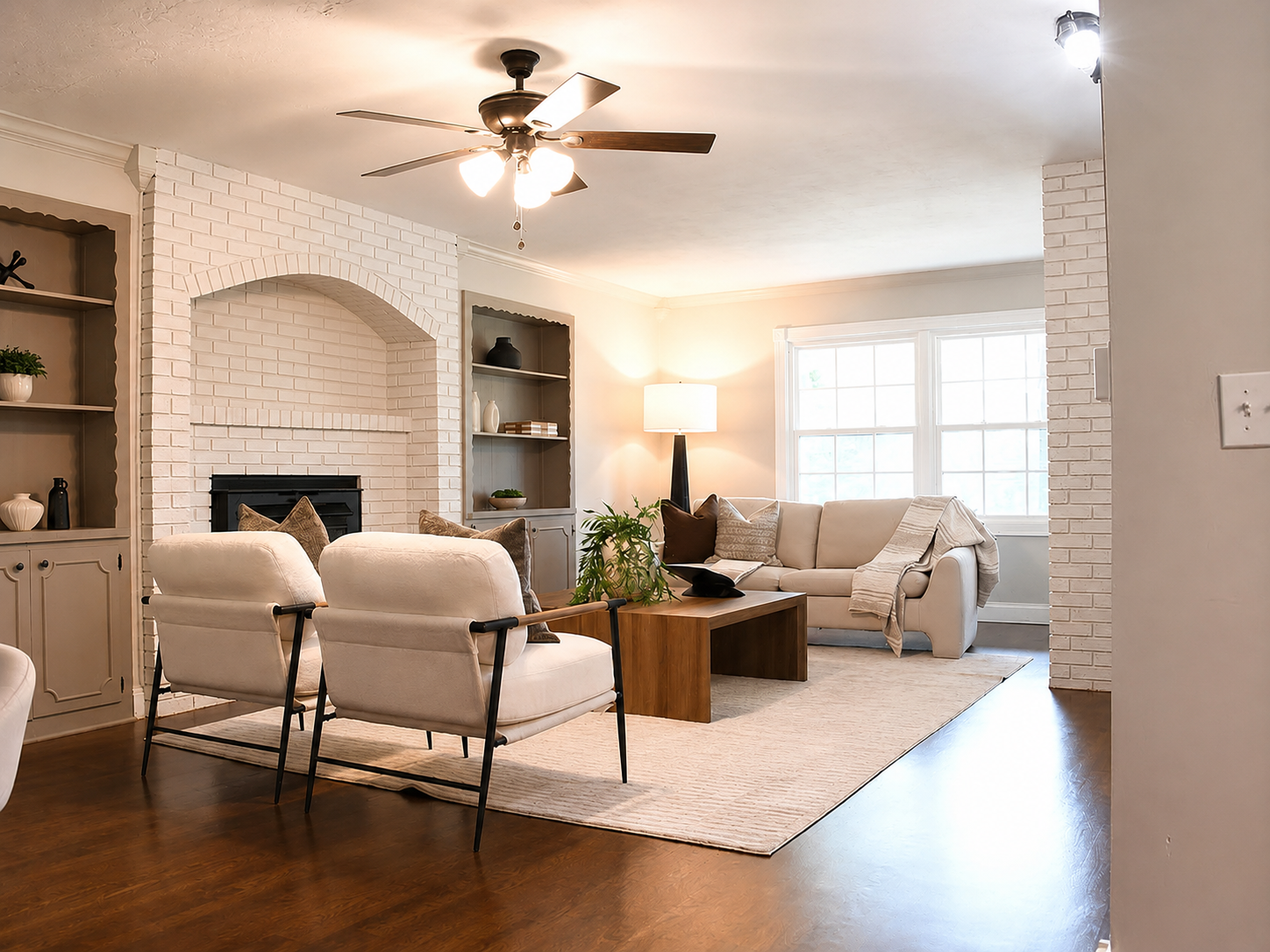 Living room with painted white brick fireplace, built-in shelves and modern-neutral seating after vacant home staging on West Ellison Drive, Springfield, MO