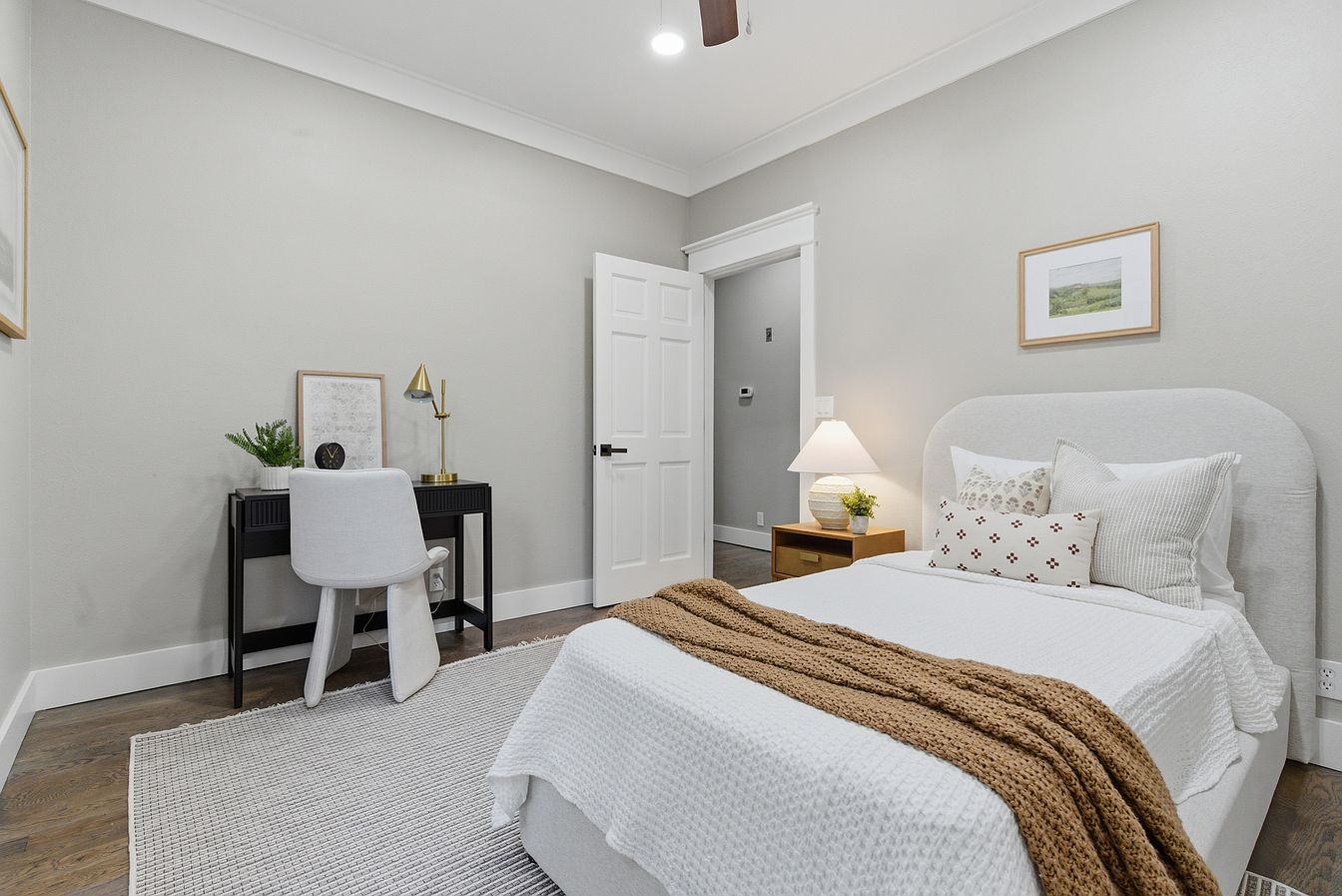 Guest bedroom staged with upholstered bed, black desk and brass lamp - Wilderness Road, Rogersville, MO