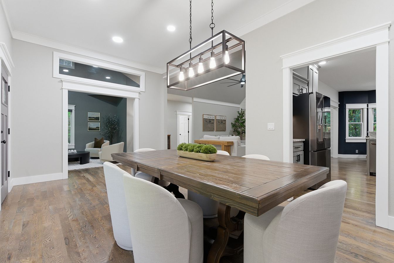 Open-plan dining area with farmhouse table looking into sitting room and kitchen after staging - Wilderness Road, Rogersville, MO