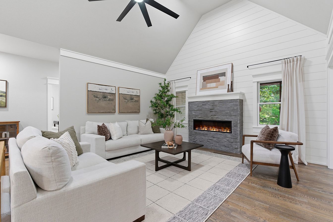 Vaulted living room with white sofas, stacked-stone electric fireplace and shiplap wall after vacant home staging on Wilderness Road, Rogersville, MO