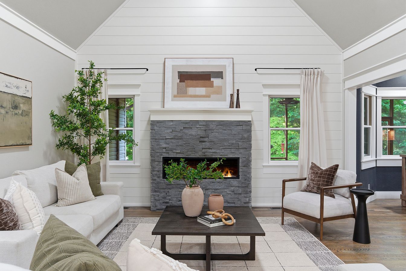Living room stacked-stone fireplace with mantel art, olive tree and wood-frame accent chair - Wilderness Road home staging, Rogersville, MO