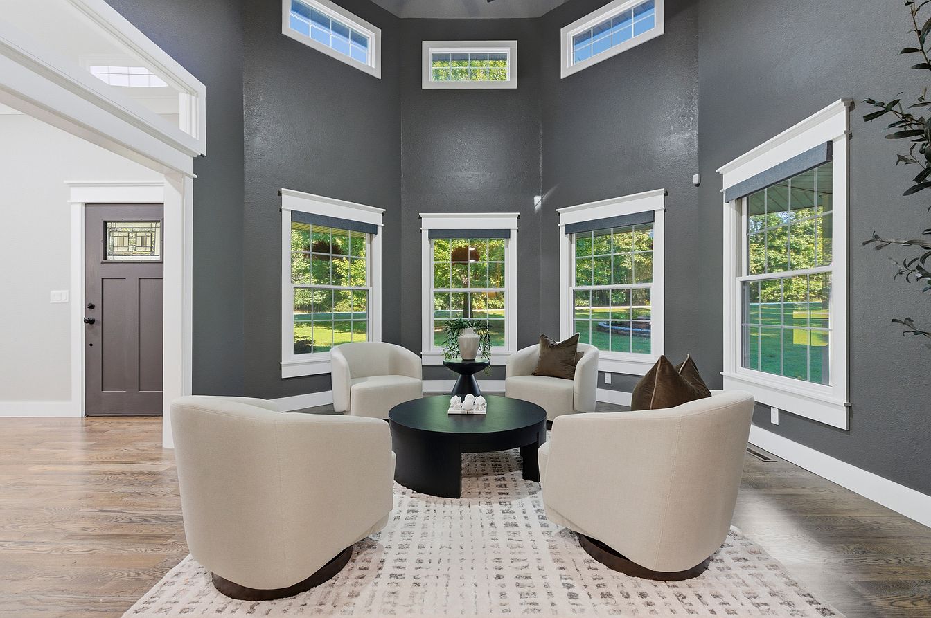 Two-story charcoal sunroom with four boucle swivel chairs and black coffee table after home staging - Wilderness Road, Rogersville, MO